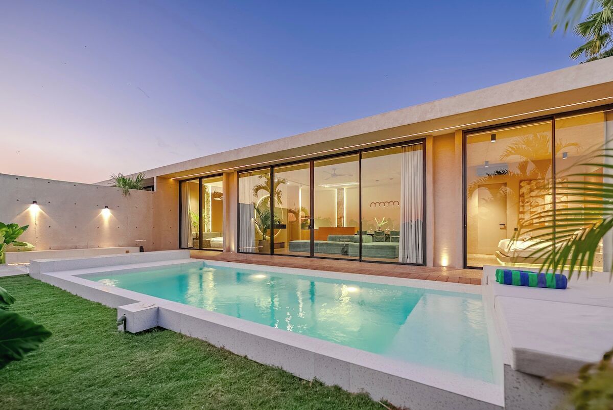 A modern house with a swimming pool, large glass doors, and a well-lit interior.