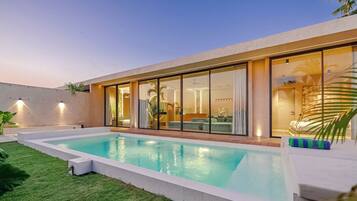 A modern house with a swimming pool, large glass doors, and a well-lit interior.