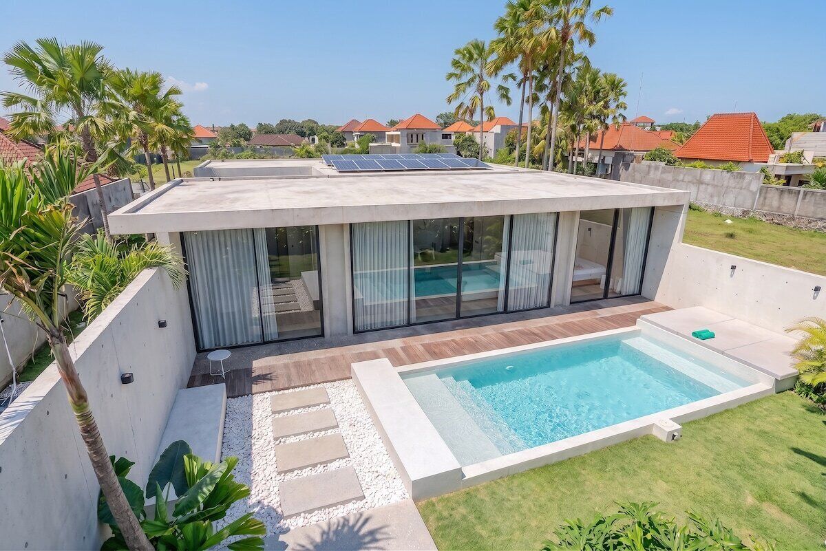 A modern house with a swimming pool, solar panels, and a view of neighboring houses.