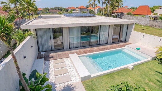 Une maison moderne dotée d’une piscine, de panneaux solaires et offrant une vue sur les maisons voisines.