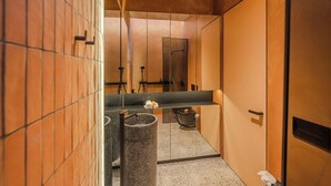 Une salle de bain moderne avec un grand miroir, un lavabo et une poubelle.