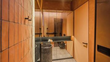 A modern bathroom with a large mirror, a sink, and a trash can.