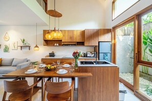 Una cocina moderna con armarios de madera, una mesa de comedor preparada para cuatro personas y un ventanal con vistas a zonas verdes.
