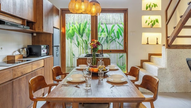 Una cucina moderna con mobili in legno, un tavolo da pranzo per sei persone e vista su del verde dalla finestra.