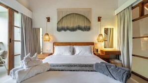 Una camera d'albergo con un letto grande, due abat-jour, un arazzo e uno specchio.