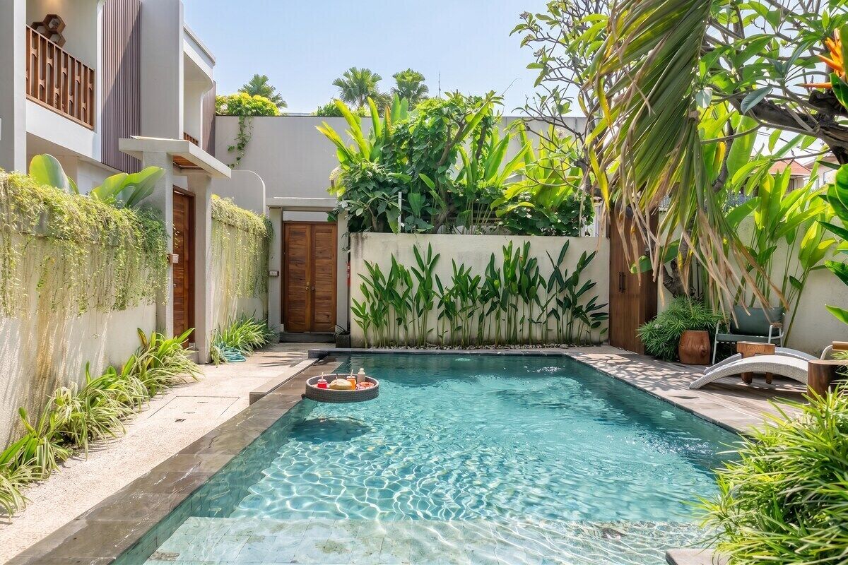 Ein Schwimmbecken mit einer schwimmenden Bar, umgeben von üppiger Vegetation und einem modernen Gebäude.