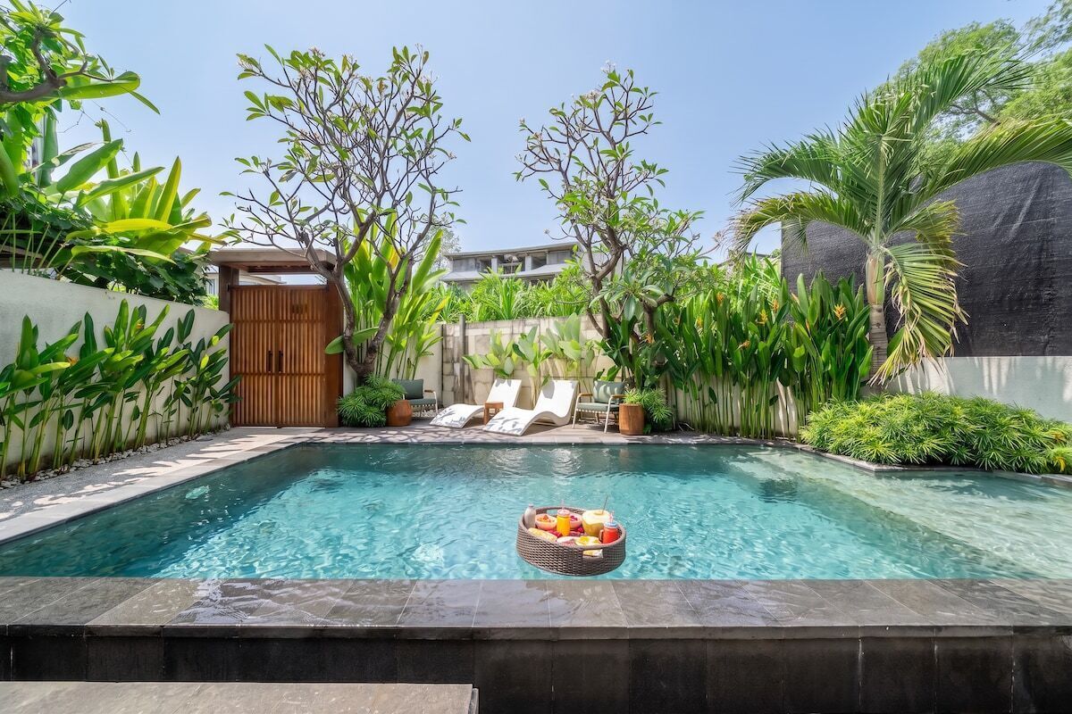 Une piscine avec un panier de fruits flottant à la surface et, au fond, une porte en bois.