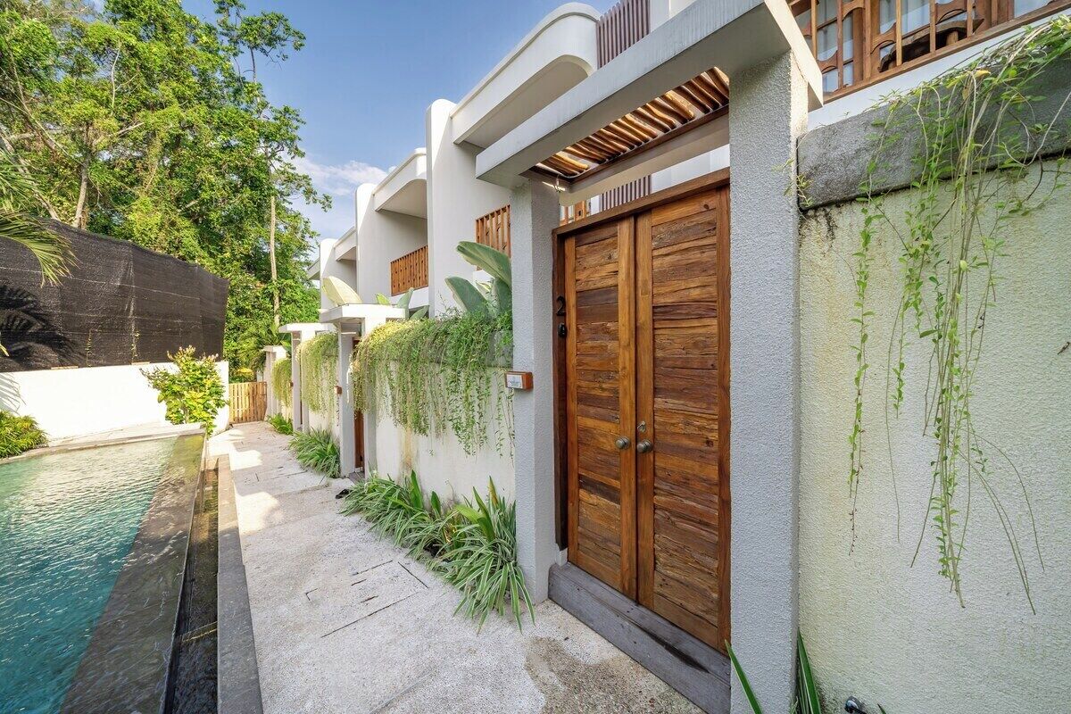 A modern building with a swimming pool, wooden doors, and a garden area.