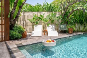 Un área de piscina con sillones de descanso y un bar flotante.