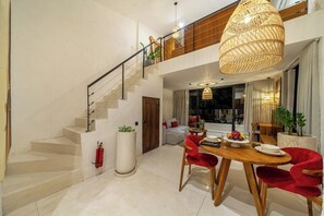 A modern interior with a staircase, dining area, and a large window. - Serene 1BR Flat in Ubud's Centre • Pool • Kitchen (Gianyar Regency)