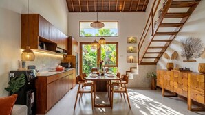 Una cucina moderna con mobili in legno, un tavolo da pranzo imbandito per sei persone e una scala che conduce a un piano superiore.