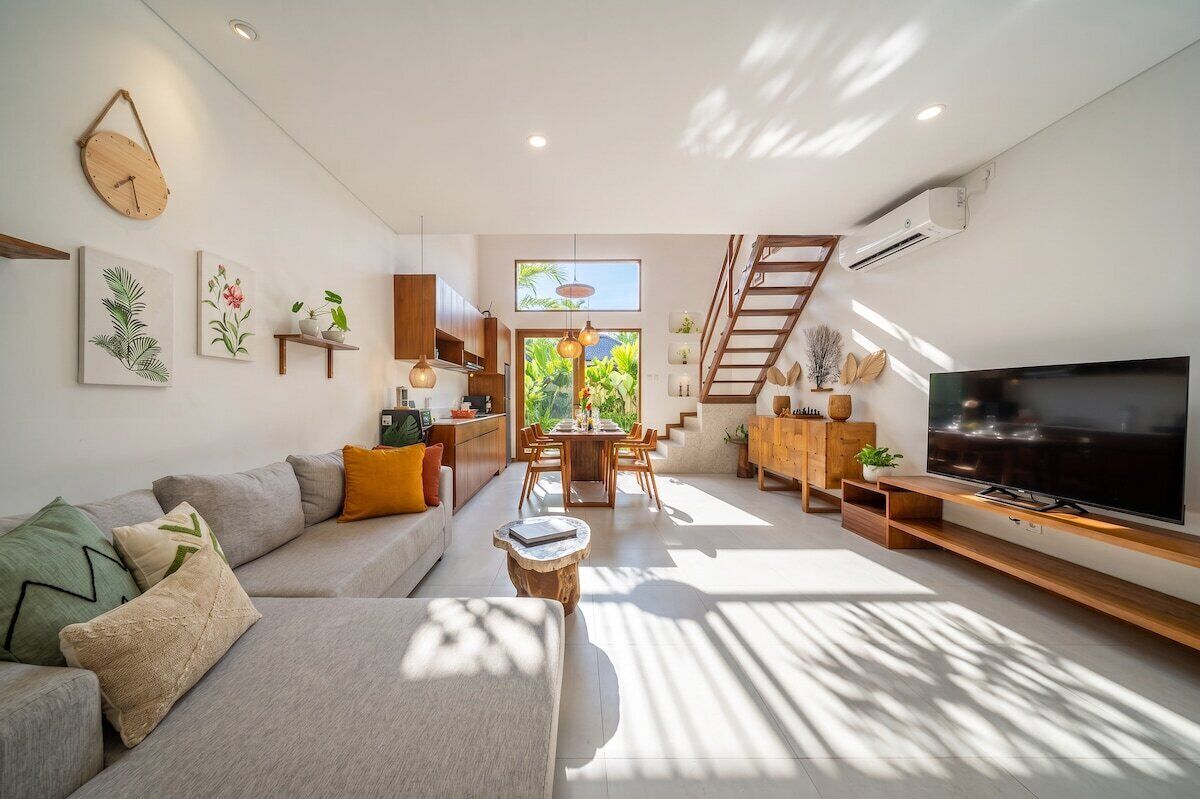A modern living room with a sofa, TV, and dining area.