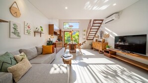 Un soggiorno moderno con divano, TV e zona pranzo.