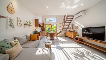 A modern living room with a sofa, TV, and dining area.