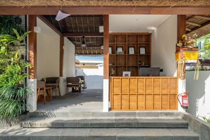 A reception area with a wooden desk, chairs, and a fire extinguisher. - Cozy 1BR Flat in Ubud • Pool • Kitchen • Garden (Gianyar Regency)