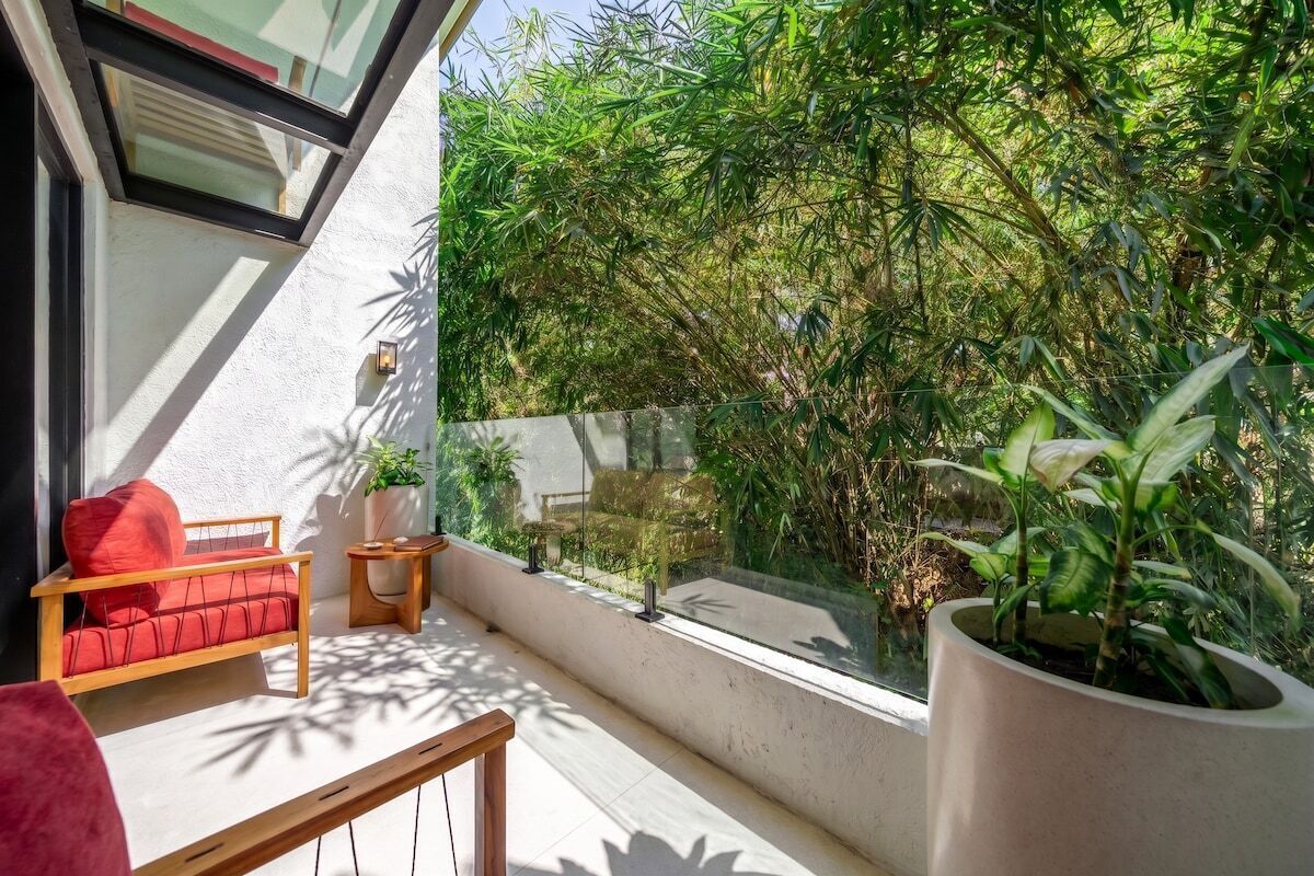 Un balcon avec un canapé rouge, une petite table et une plante en pot.