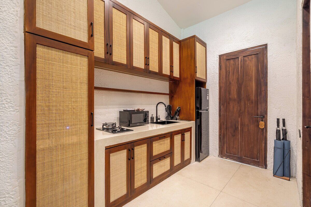 A kitchen with wooden cabinets, a microwave, a sink, and a refrigerator.