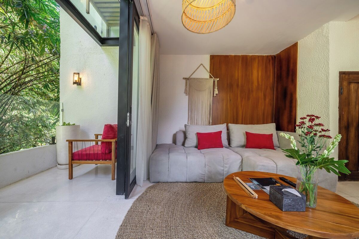 A modern living room with a sofa, a coffee table, a chair, and a hanging light fixture.