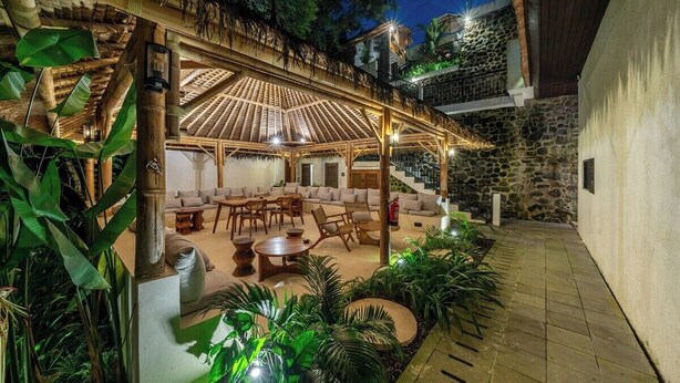 An outdoor patio with a thatched roof, seating area, and lush greenery. - Chic 1BR in Tropical Ubud • Pool • Kitchen • Patio (Gianyar Regency)