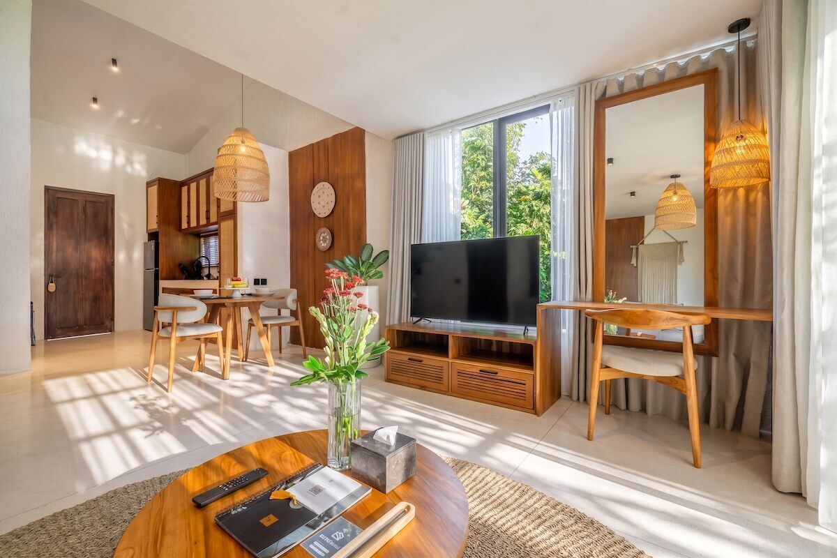 Un salon moderne avec un téléviseur à écran plat, des meubles en bois et une grande fenêtre agrémentée de rideaux.