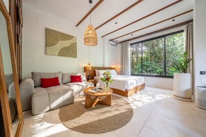 A modern bedroom with a bed, sofa, and a round coffee table. - Stylish 1BR in Ubud w Pool, Patio, Private Kitchen (Gianyar Regency)