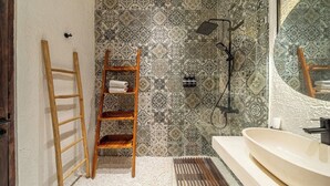 Un baño con una escalera de madera, un lavabo y baldosas estampadas.