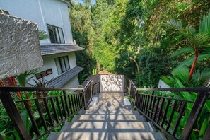A staircase leading to a white building surrounded by lush greenery. - Designer 1BR Flat in Ubud w Pool, Garden & Kitchen (Gianyar Regency)