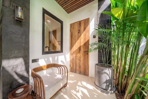 A modern interior with a wooden door marked with the number 2, a seating area with a cushioned bench, and a large potted plant. - Chic 1BR • Pool • Private Kitchen • Central Ubud (Kabupaten Gianyar)