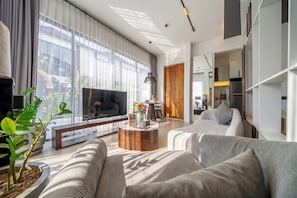 A modern living room with a large flat-screen TV, a sofa, a coffee table, and a dining area. - Best Ubud's 1BR w Pool, Patio & Private Kitchen (Kabupaten Gianyar)