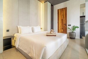 A modern bedroom with a large bed, bedside tables, a wooden door, a potted plant, and a built-in wardrobe. - Hidden 1BR Gem in Central Ubud w Pool & Kitchen (Kabupaten Gianyar)