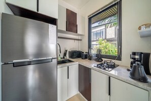 A modern kitchen with stainless steel appliances, a window with a view of greenery, and a countertop with various kitchen items. - Hidden 1BR Gem in Central Ubud w Pool & Kitchen (Kabupaten Gianyar)