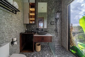 Un bagno moderno con uno specchio grande, un lavandino con una conca, una doccia e vista su del verde all'esterno.