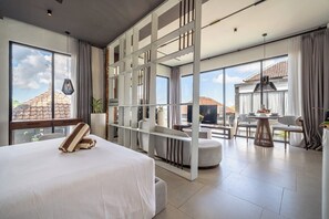 Una camera d'hotel moderna con un letto grande, un'area salotto con un tavolo e vista all'esterno.