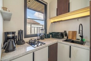 Eine kompakte Küche mit Gaskochfeld, Kaffeemaschine, Toaster und Spüle.