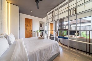 A modern bedroom with a large bed, a wooden door, and a view of the outdoors. - Best Ubud's 1BR Apartment w Pool, Patio & Kitchen (Ubud)