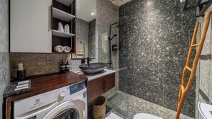 Un baño moderno con lavadora, lavamanos, ducha y retrete.