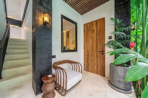 A staircase leading to a room with a wooden door, a bench, and a large potted plant. - Modern 1BR Flat in Ubud w Pool, Patio & Kitchen (Kabupaten Gianyar)