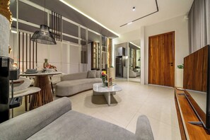A modern living room with a sectional sofa, a coffee table, and a TV. - Serene 1BR Stay in Ubud w Pool & Private Kitchen (Ubud)