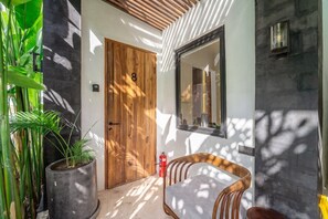 Ein modernes Interieur mit einer Holztür, einem Blumentopf, einem Stuhl und einem wandmontierten Spiegel.