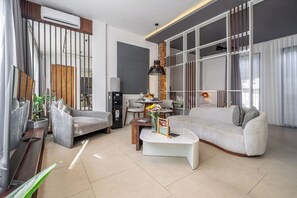Ein modernes Wohnzimmer mit einer Couch, Sesseln, einem Couchtisch und einem Fernseher.