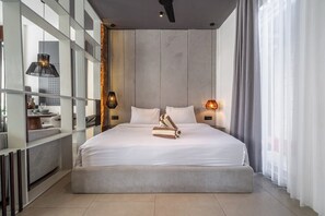 Ein modernes Hotelzimmer mit einem großen Bett, einem integrierten Schreibtisch und Blick auf die Stadt.