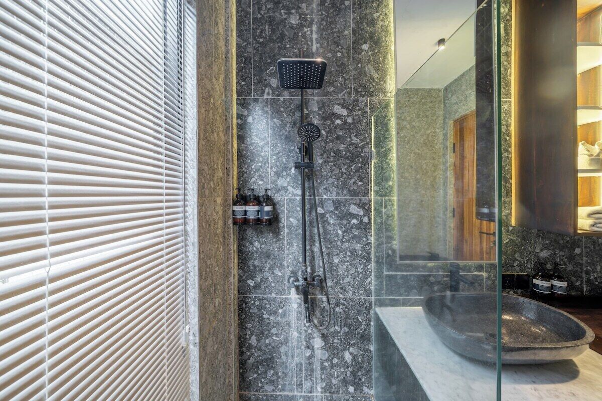 Ein modernes Badezimmer mit einer gläsernen Duschkabine, einem мраморной Waschbecken und einem hölzernen Waschtisch.
