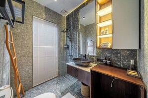 Ett modernt badrum med en stor spegel, ett fristående handfat och en duschhörna.