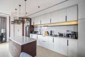 A modern kitchen with a central island, white cabinetry, and a marble countertop. - Cozy 3BR in Central Ubud w Pool, Bathtub & Kitchen (Kabupaten Gianyar)