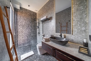 Un bagno moderno con un lavandino grande, pareti in marmo scuro e una scala in legno.