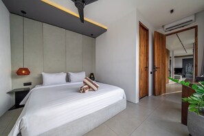A modern bedroom with a large bed, bedside tables, a wall-mounted light, and a potted plant. - Cozy 3BR in Central Ubud w Pool, Bathtub & Kitchen (Kabupaten Gianyar)
