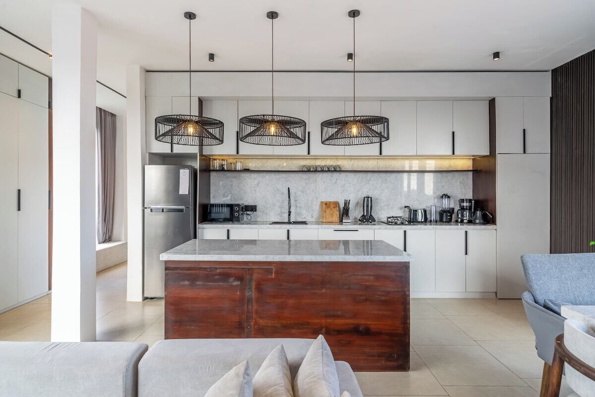 A modern kitchen with a central island, pendant lighting, and a built-in oven.