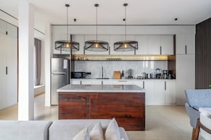 A modern kitchen with a central island, pendant lighting, and a built-in oven. - Cozy 3BR in Central Ubud w Pool, Bathtub & Kitchen (Kabupaten Gianyar)
