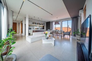 A modern living room with a sofa, coffee table, and dining area. - Cozy 3BR in Central Ubud w Pool, Bathtub & Kitchen (Kabupaten Gianyar)