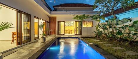 A modern house with a swimming pool, large windows, and a well-maintained garden.